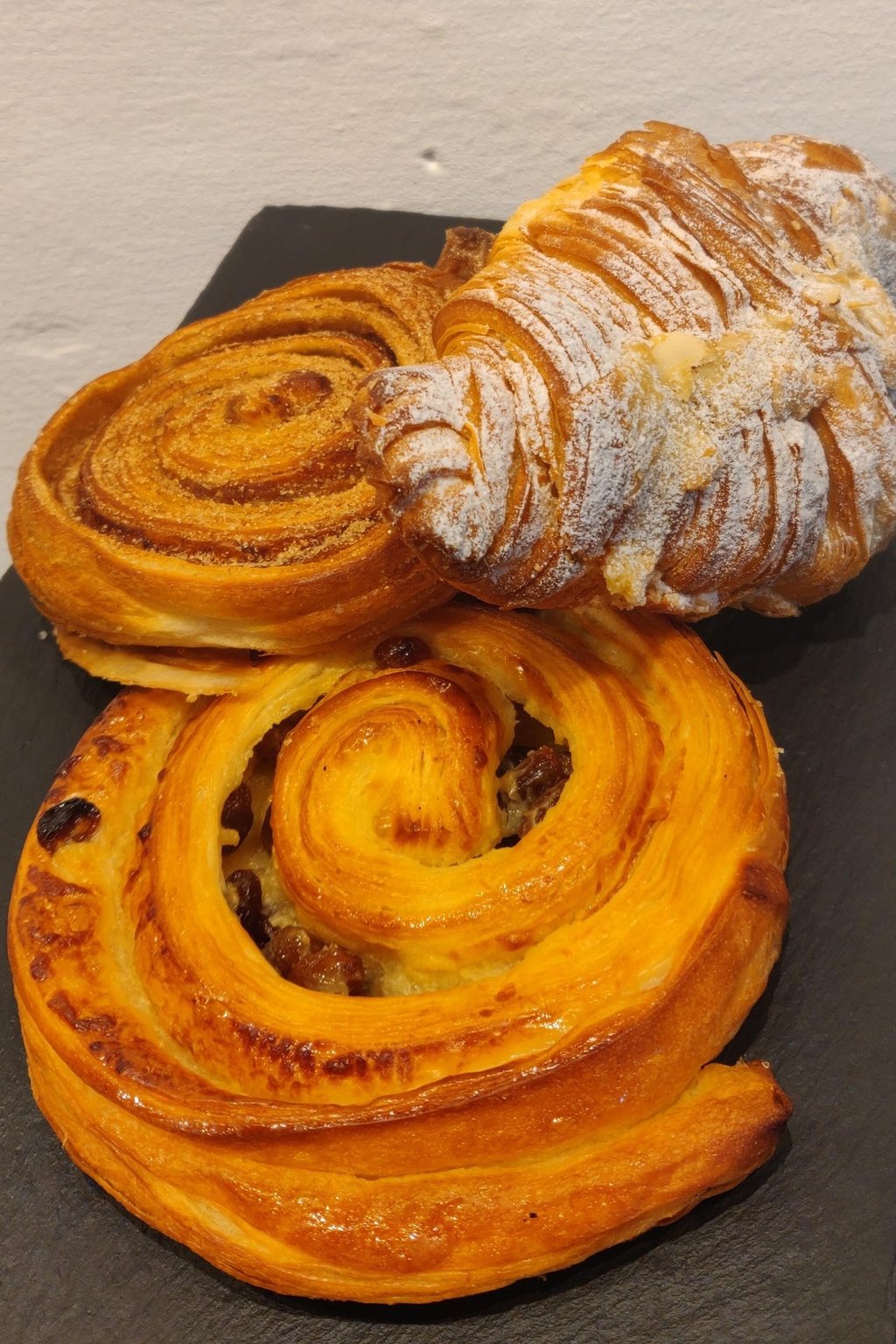 A pain au raisin and an almond croissant on a slate board